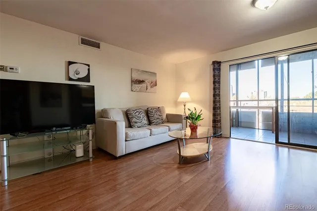 a living room with furniture a flat screen tv and wooden floor