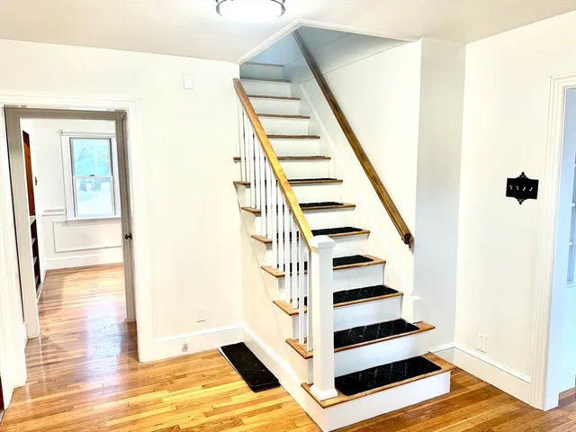 a view of a living room with wooden floor and stairs