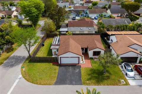 an aerial view of a house with swimming pool and large trees