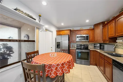 a large kitchen with stainless steel appliances granite countertop a refrigerator a stove top oven and a sink with couches