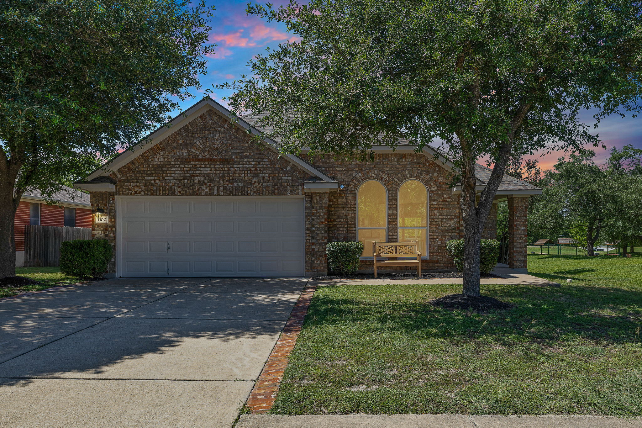 1100 Springbrook Road Pflugerville, TX 78660 - Photo 1 of 23 Classic brick exterior featuring a two-car garage and a charming arched window accent.