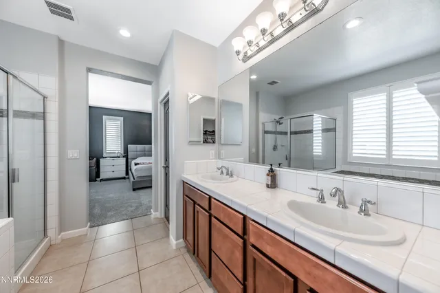 a spacious bathroom with a double vanity sink a mirror and a shower