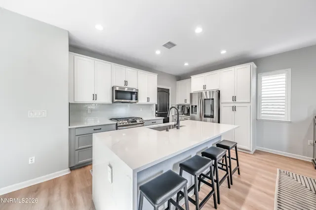 a kitchen with stainless steel appliances granite countertop a stove a refrigerator a sink a dining table and chairs