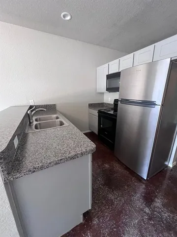 a kitchen with kitchen island a sink a refrigerator a stove and a sink