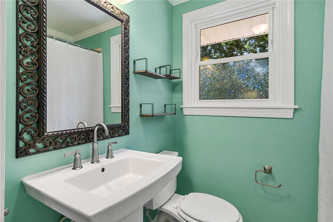 512 East Fredericks Street Anderson, SC 29621 - Photo 19 of 31 A vibrant bathroom with a pedestal sink, framed mirror, and a window for natural illumination.