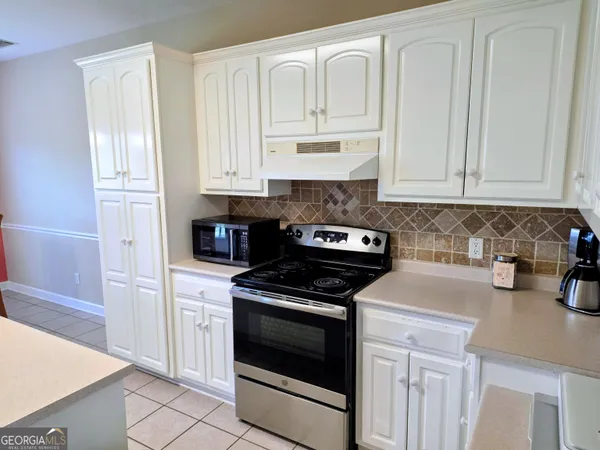 a kitchen with granite countertop white cabinets and stainless steel appliances