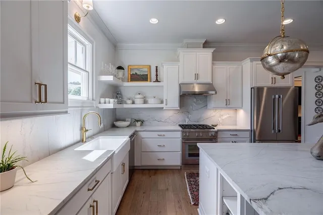 a kitchen with stainless steel appliances granite countertop a sink a stove and a refrigerator