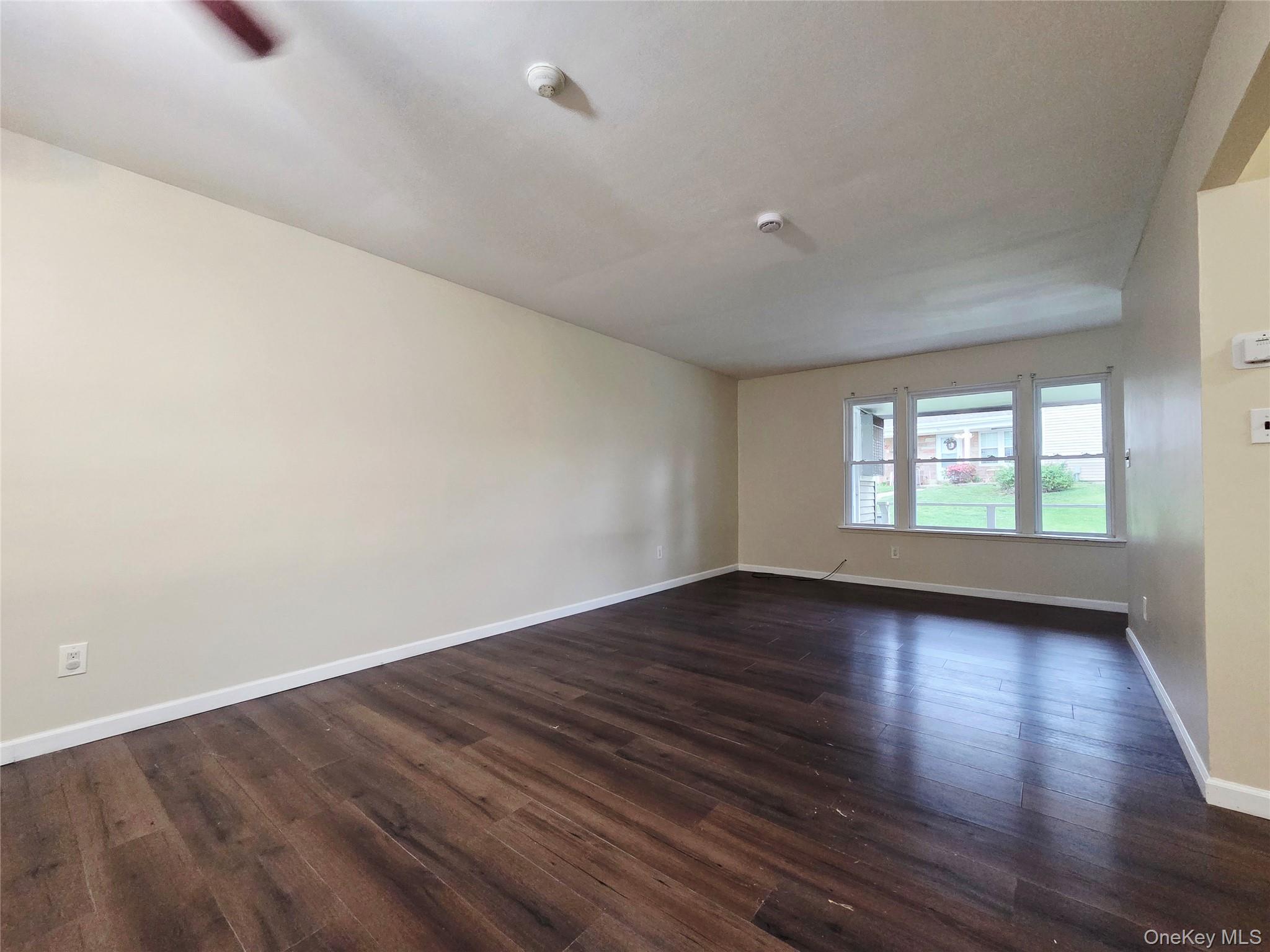 5 Independence Court, Unit 5A Ridge, NY 11961 - Photo 2 of 9 a view of an empty room with wooden floor and window