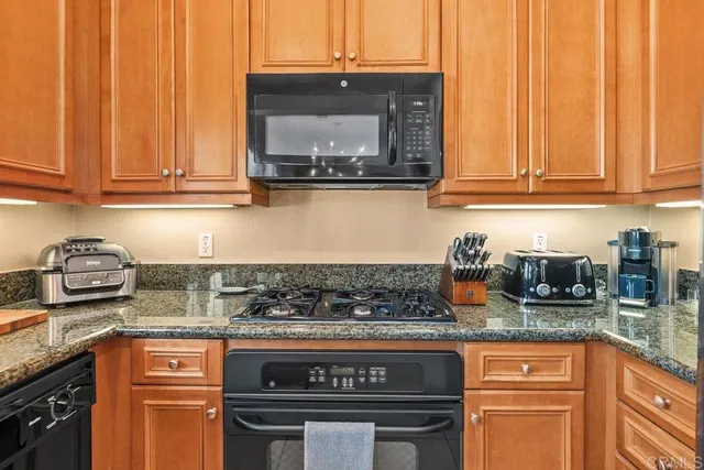 a kitchen with granite countertop stainless steel appliances a stove a sink and cabinets