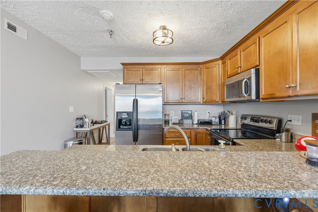 100 Taylor Street, Unit 302 Colonial Beach, VA 22443 - Photo 6 of 30 Kitchen featuring brown cabinets, stainless steel