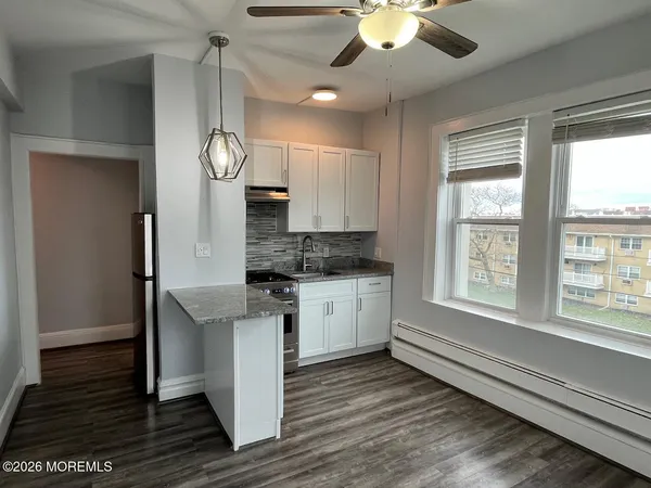 a kitchen with a refrigerator a stove cabinets and wooden floor