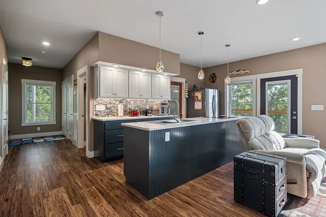 a living room with stainless steel appliances kitchen island granite countertop furniture a large window and wooden floor