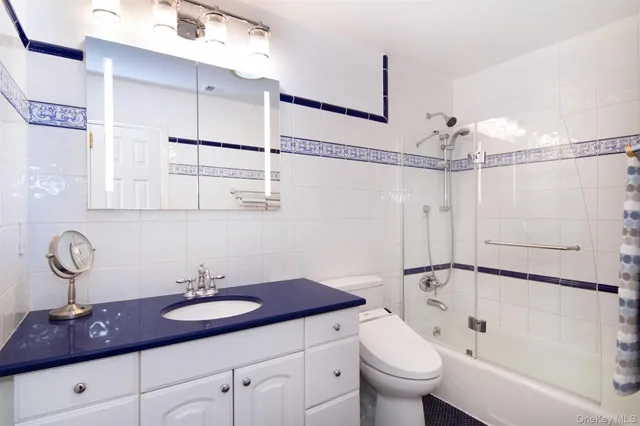 a bathroom with a granite countertop sink a toilet a mirror and shower