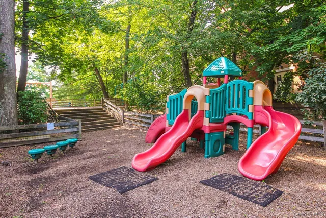 a view of a park with slide and a wooden fence