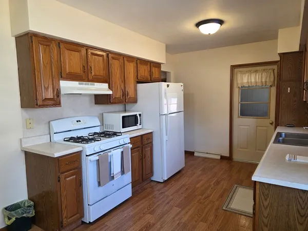 a kitchen with a stove a refrigerator and wooden floor