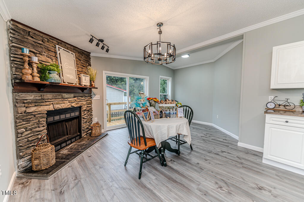 2245 Docs Road Lillington, NC 27546 - Photo 45 of 54 a dining room with furniture a fireplace and wooden floor