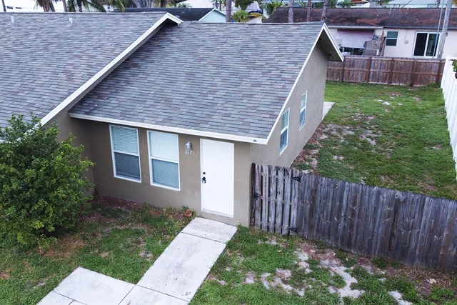 a brick house with a small yard plants and large tree