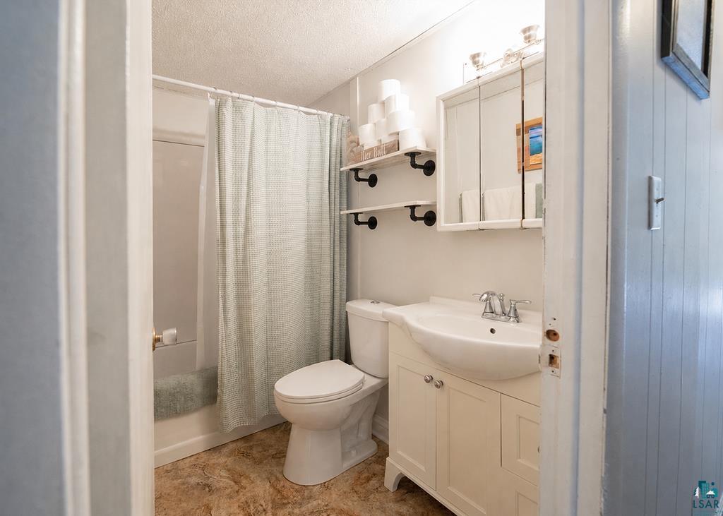 216 13th Street Proctor, MN 55810 - Photo 12 of 18 Full bathroom featuring a white vanity with integrated sink, chrome faucet, and a wall-mounted medicine cabinet with integrated lighting