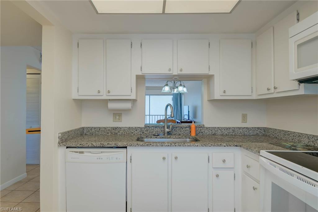 3030 Binnacle Drive, Unit 305 Naples, FL 34103 - Photo 18 of 25 a kitchen with stainless steel appliances granite countertop white cabinets sink and granite counter tops