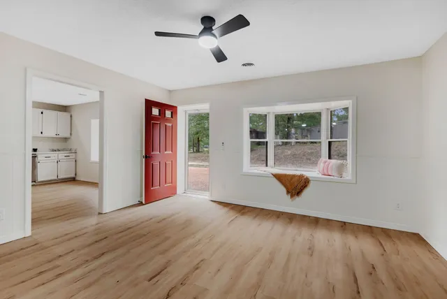 a view of an empty room with wooden floor and a window
