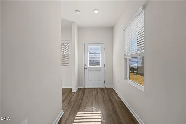 a view of a hallway with wooden floor and a bathroom