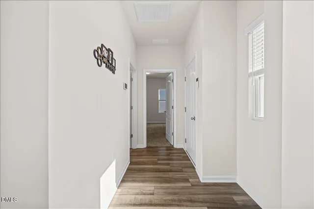 a view of a hallway with wooden floor and a bathroom