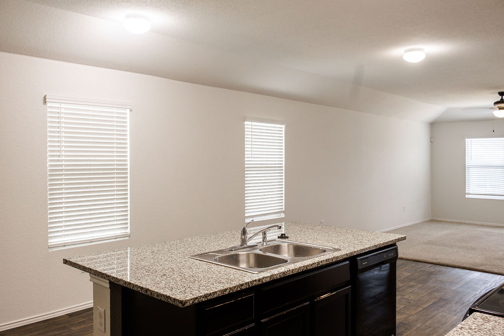 14915 Talus Road Manor, TX 78653 - Photo 20 of 20 An open floor plan connects the kitchen island to a carpeted living space.
