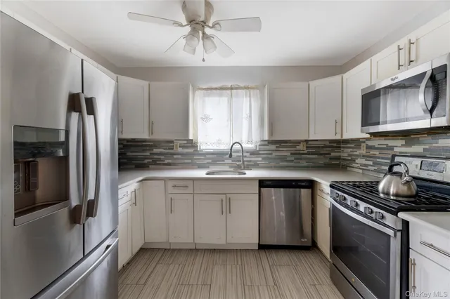 a kitchen with stainless steel appliances granite countertop a stove a sink dishwasher a refrigerator and a microwave oven with wooden floor