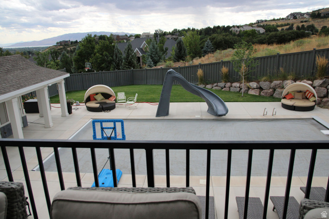 7 Elk Court Alpine, UT 84004 - Photo 3 of 10 Expansive outdoor living area featuring a covered patio, concrete deck surrounding a covered swimming pool, and a sloped grass lawn