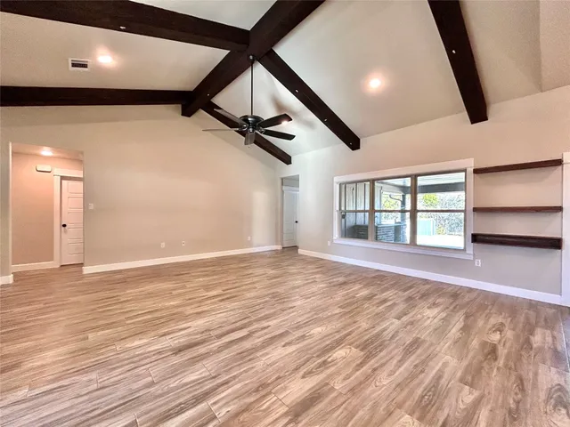 a view of an empty room with window and wooden floor