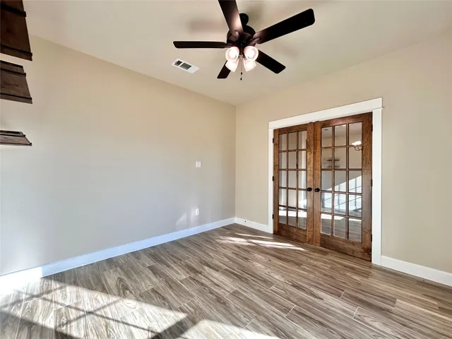 a view of an empty room with a window and wooden floor