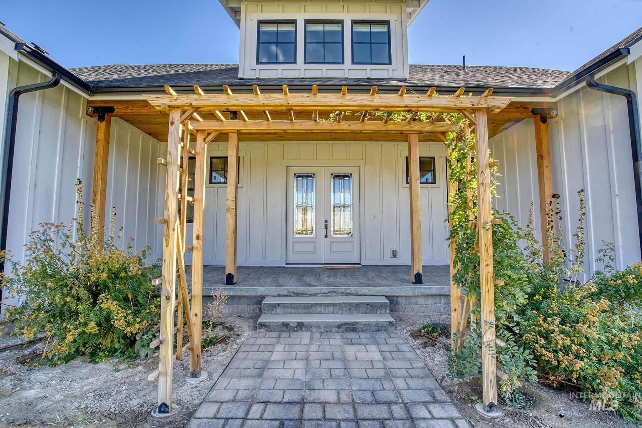 876 Coyote Gulch Road Adrian, OR 97901 - Photo 2 of 50 Board and batten exterior with a gabled roofline, double entry doors, a wooden pergola, and a paver pathway