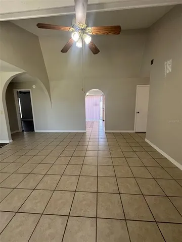 a view of an empty room and chandelier fan