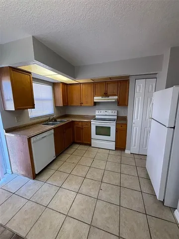 a kitchen with granite countertop a stove a sink and a refrigerator