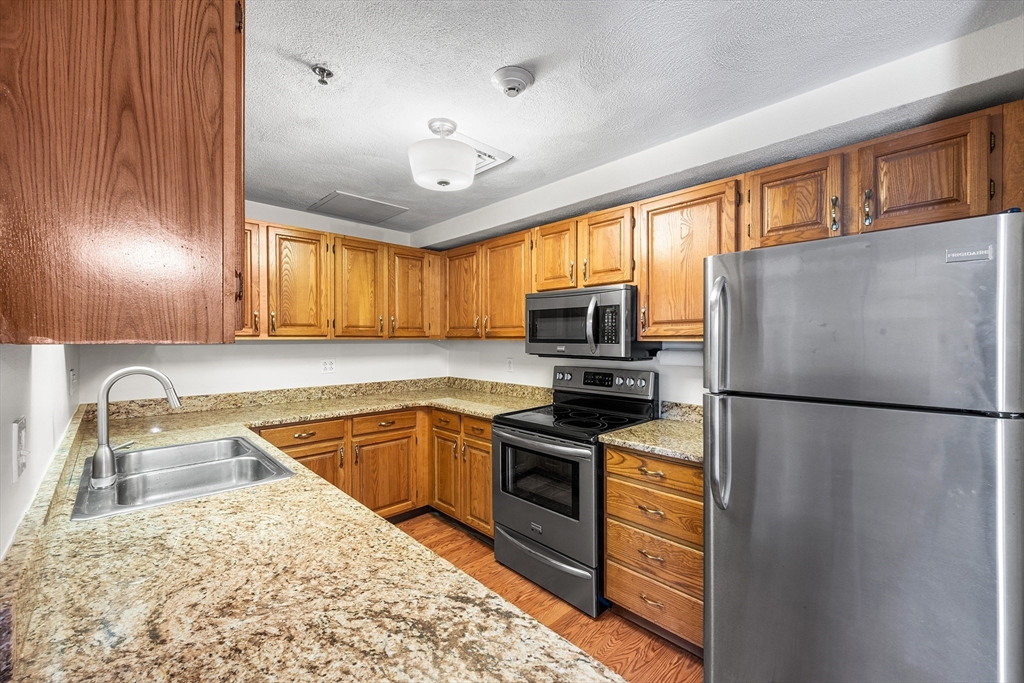 39 Parlin Street, Unit 503 Everett, MA 02149 - Photo 6 of 24 a kitchen with granite countertop stainless steel appliances a refrigerator sink and microwave