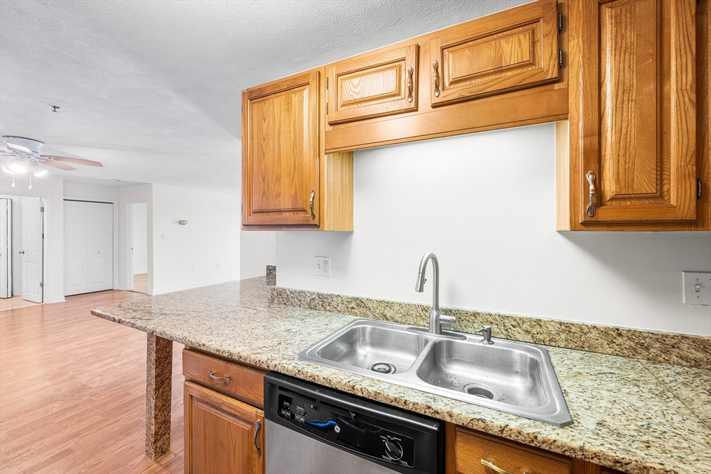 39 Parlin Street, Unit 503 Everett, MA 02149 - Photo 8 of 24 a kitchen with granite countertop a sink and a wooden cabinets