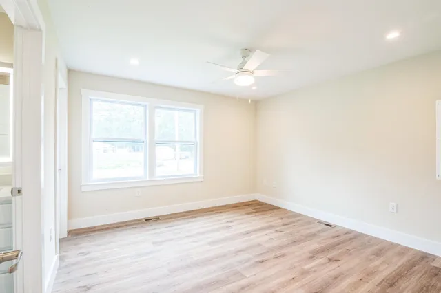 an empty room with wooden floor and windows