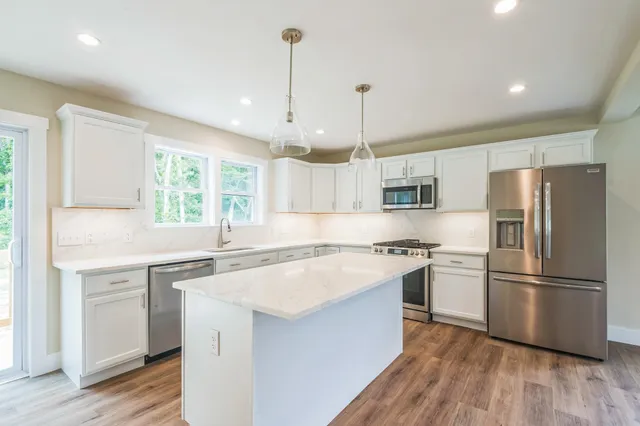 a kitchen with a refrigerator a sink and wooden floor