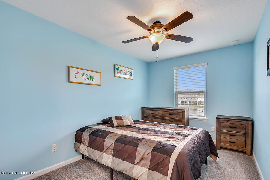 122 Nelson Lane St. Johns, FL 32259 - Photo 15 of 33 a bedroom with a bed and a chandelier