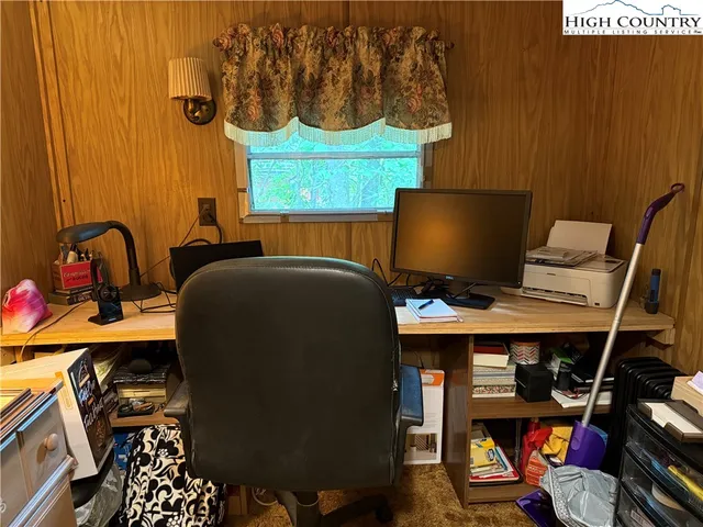 a bedroom with a bed and a computer on a desk next to a window