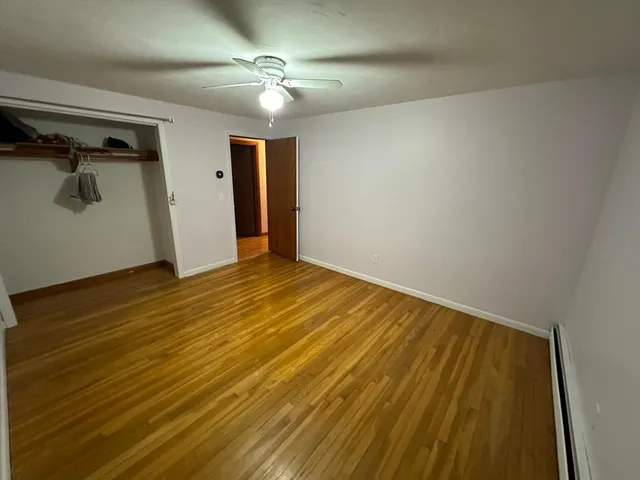 a bedroom with a bed and dresser with wooden floor