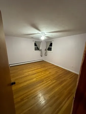 a sign that is sitting in front of a house with large trees