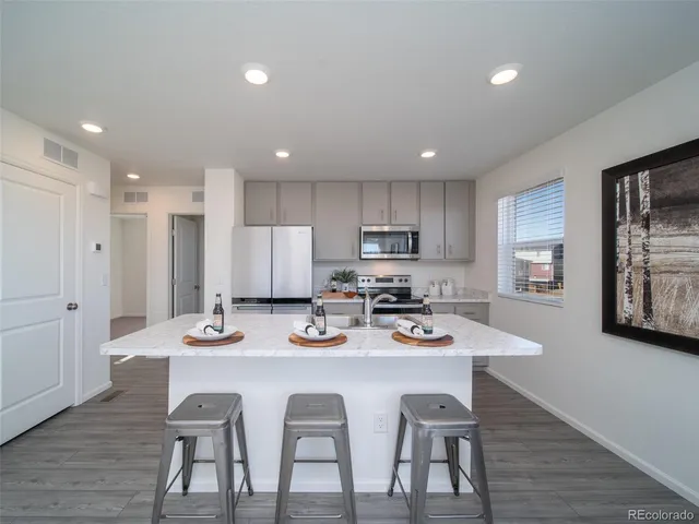 a kitchen with stainless steel appliances granite countertop a dining table chairs refrigerator and microwave