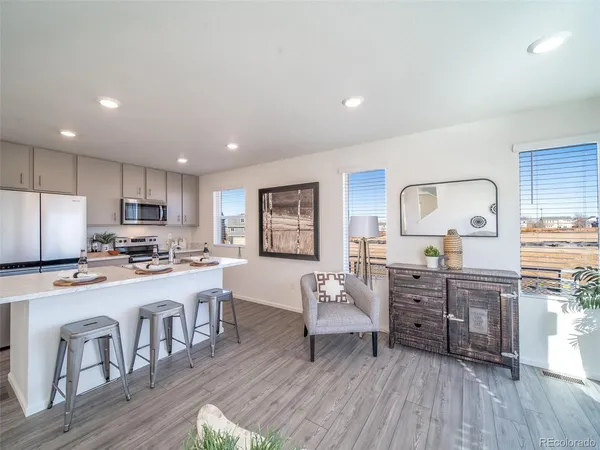 a kitchen with stainless steel appliances granite countertop a stove top oven a sink dishwasher a dining table and chairs with wooden floor