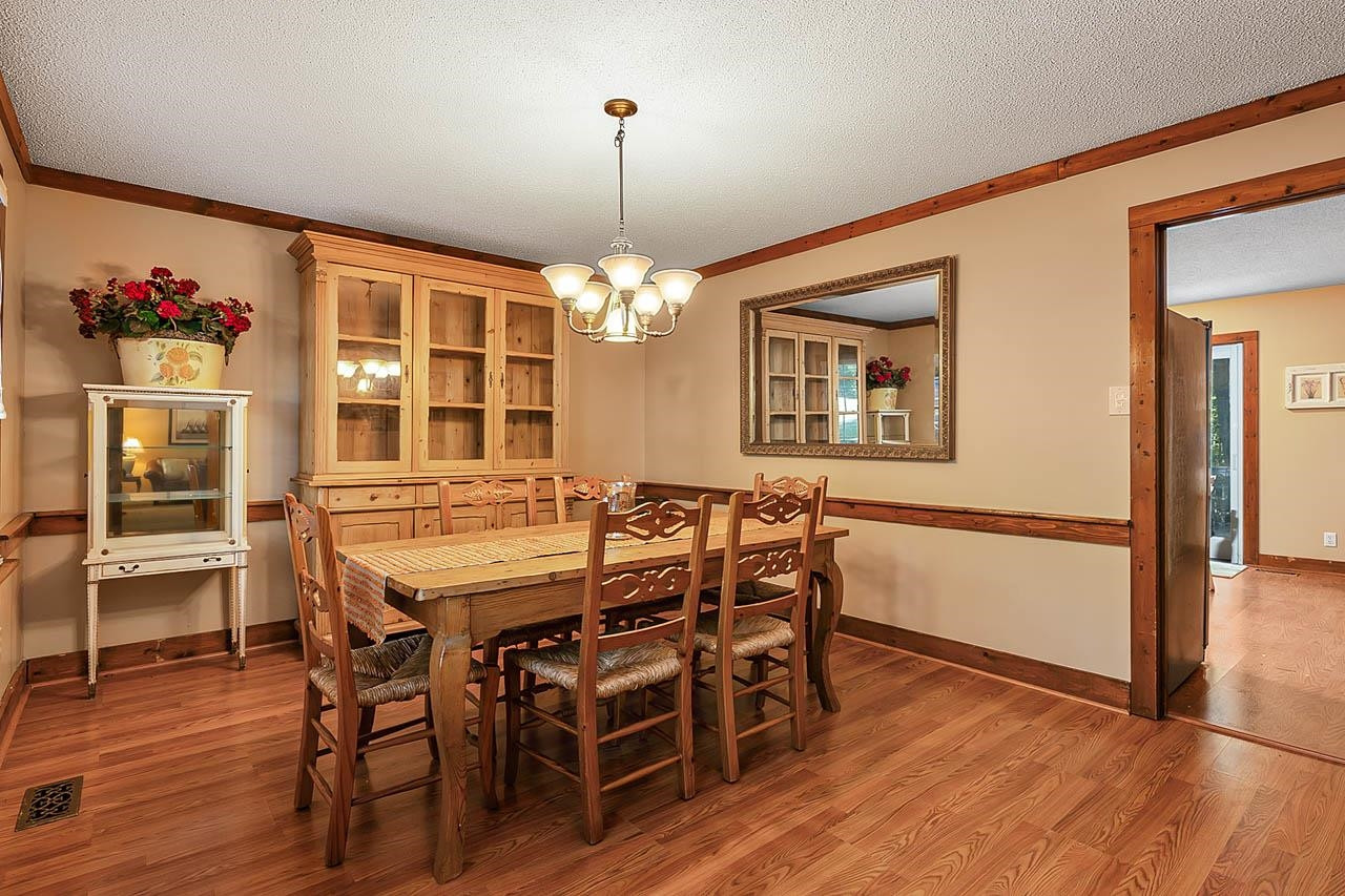 3109 Barnsley Lane Raleigh, NC 27604 - Photo 3 of 50 a dining room with wooden floor a chandelier a wooden table and chairs