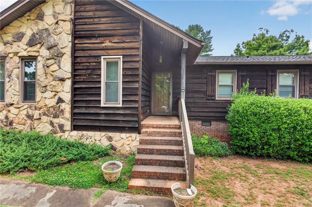 112 Holliday Lane Pendleton, SC 29670 - Photo 2 of 42 A charming rustic home featuring a stone facade and natural wood siding, offering a cozy retreat.