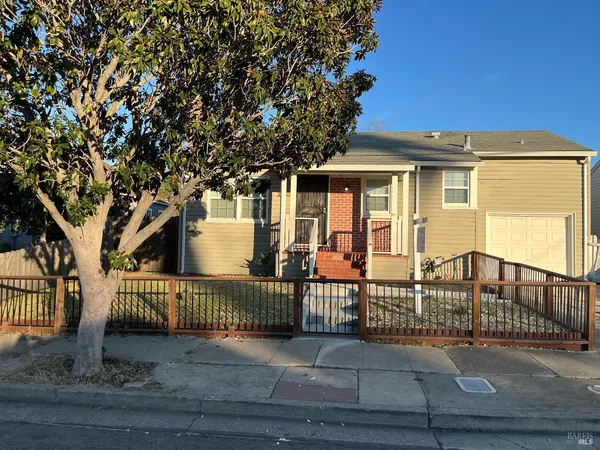 a view of a house with a small yard and wooden fence