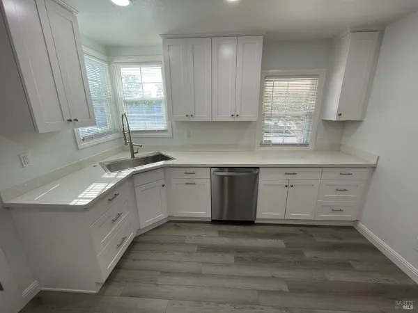 a kitchen with white cabinets appliances a sink and a window