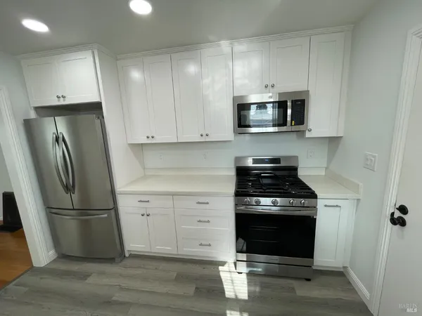 a kitchen with stainless steel appliances white cabinets and a stove top oven