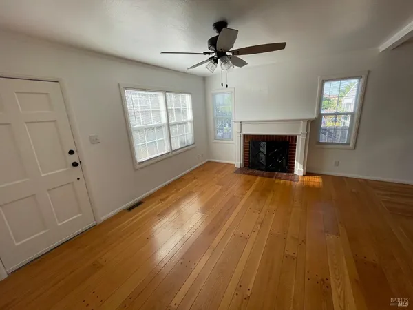 a view of empty room with wooden floor and fireplace